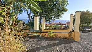 A patio area with a bench, a small garden, and a view of the sea. - Cozy Studio in a fabulous Quinta with pool and sea view! (Funchal)