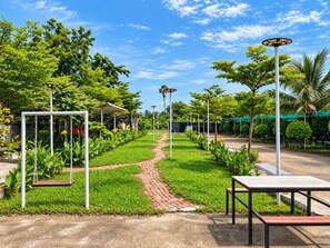 Un sentier de jardin agrémenté de balançoires, un espace de repos abrité et des lampadaires.