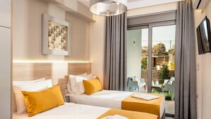 Habitación de hotel con dos camas, un ventanal grande y un televisor en la pared.