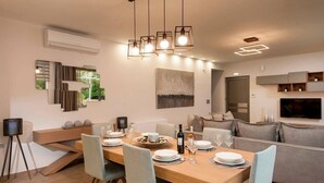 Un comedor moderno con una mesa de madera dispuesta para cuatro personas, sillas azul claro y una lámpara contemporánea arriba.