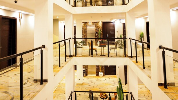 A multi-level hotel lobby with a central atrium, glass railings, and a green carpeted area. - Cape Hotel (Addis Ababa)