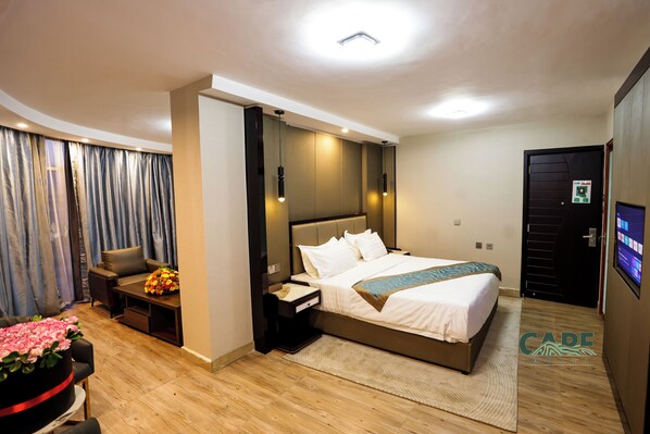 A modern hotel room with a large bed, a desk, a chair, and a TV. - Cape Hotel (Addis Ababa)