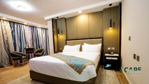 A modern hotel room with a large bed, a nightstand, a chair, and a desk. - Cape Hotel (Addis Ababa)