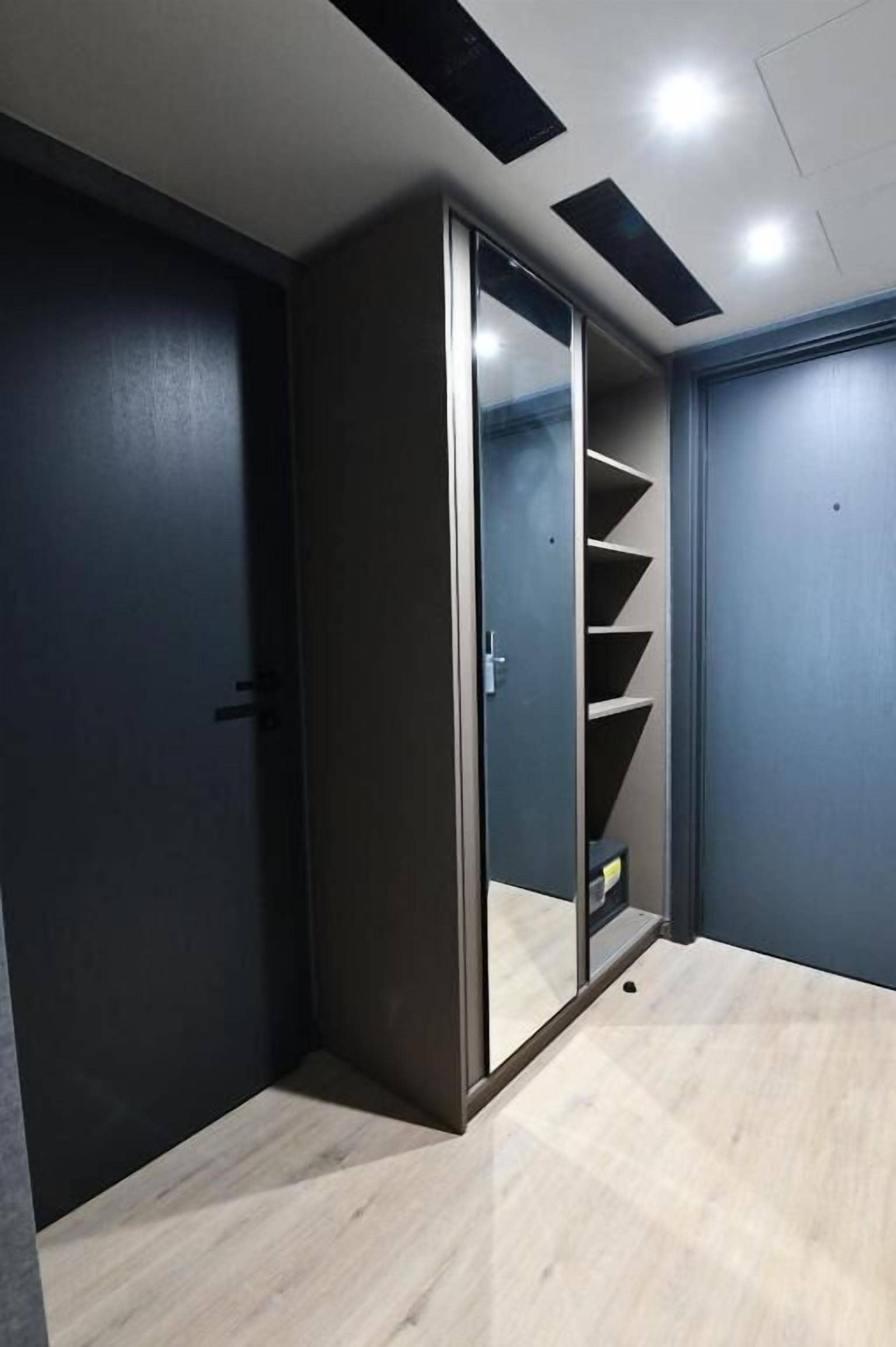 A room with a sliding door closet, a light wooden floor, and a dark wall.