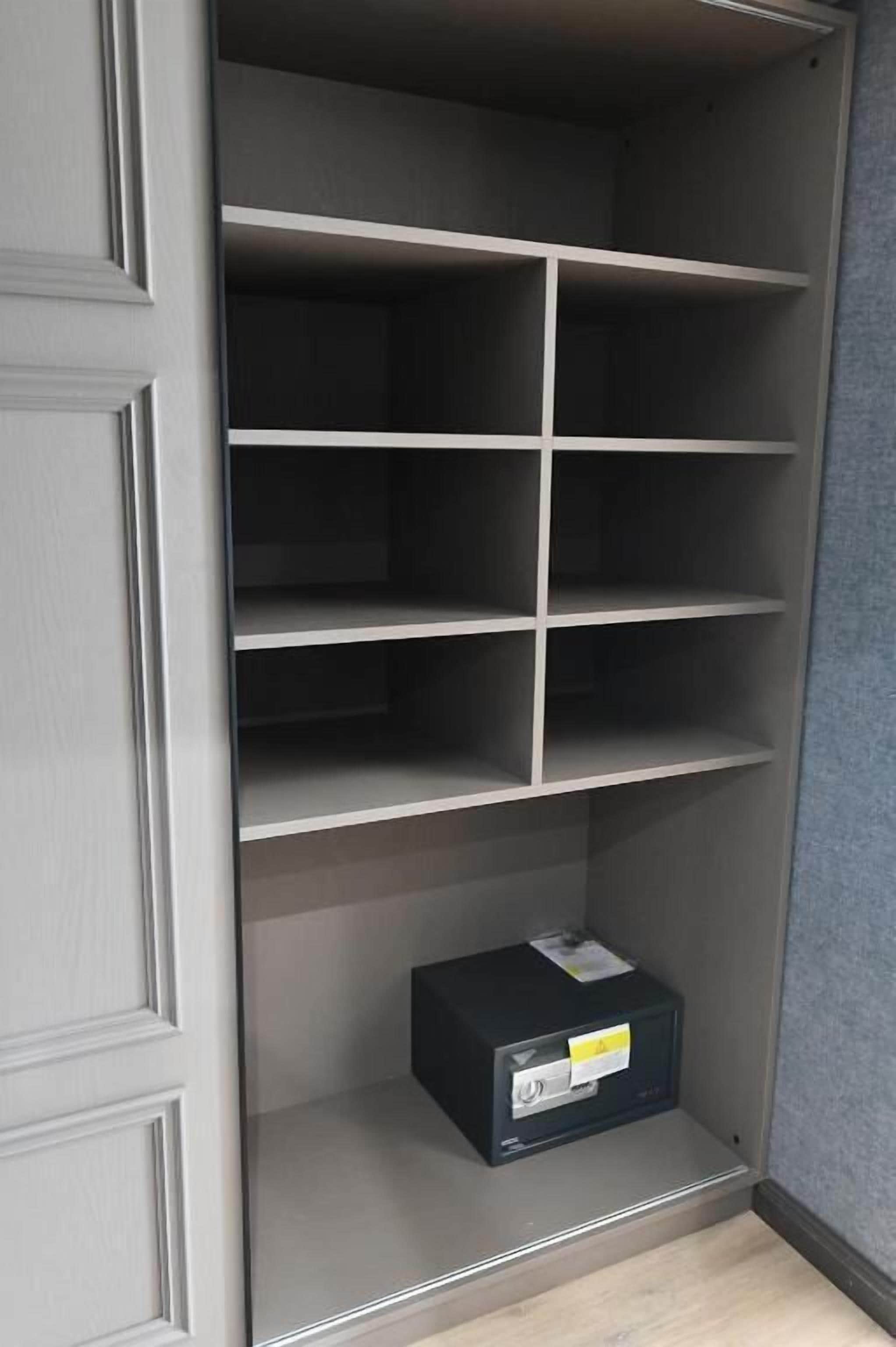 A closet with multiple shelves and a small black box on the bottom shelf.