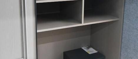 A closet with multiple shelves and a small black box on the bottom shelf.