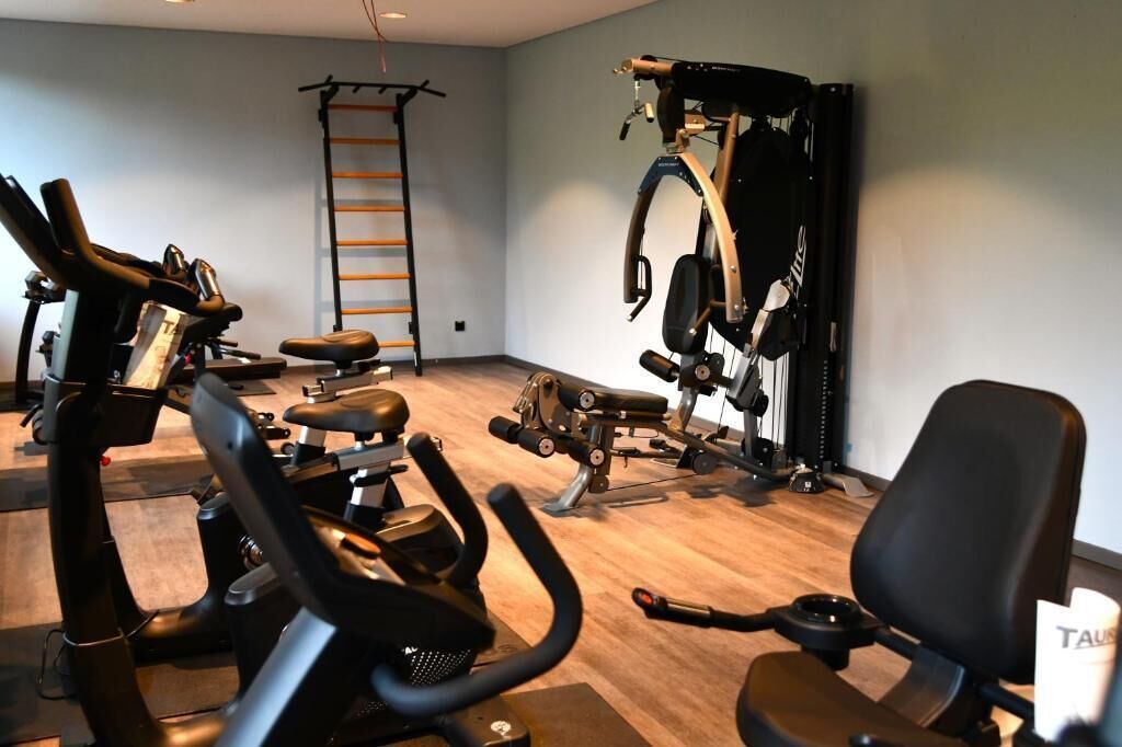 Een sportschool met trainingsapparatuur, een pull-up stang en een stoel.