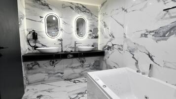 A modern bathroom with marble walls, two sinks, and a bathtub.