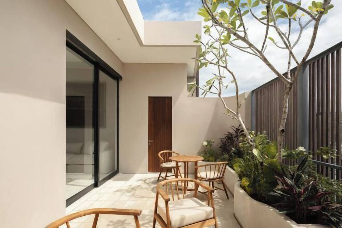 Een modern terras buiten met houten meubels en een plantenbak met diverse planten.