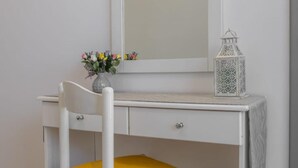 A white desk with a mirror, a yellow chair, and a small vase with flowers. - Ranias House Faliraki (Rhodes)
