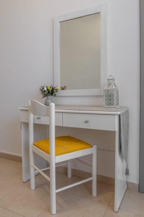 A white desk with a mirror, a yellow chair, and a small vase with flowers. - Ranias House Faliraki (Rhodes)