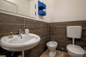 A bathroom with a white sink, a bidet, and a toilet.