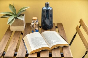 Un livre ouvert sur un banc en bois, avec une plante en pot et une bouteille à côté.
