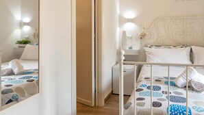 A hotel room with a bed, a nightstand, a mirror, and a wall with a 'WHITE STAR' sign. - White star rooms self-check in (Alghero)