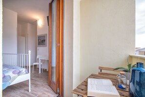 A balcony with a wooden table, a chair, a small potted plant, and a book.