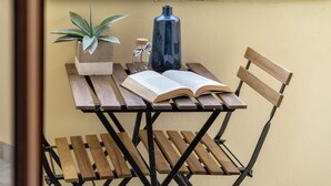 A wooden table with a book, a potted plant, and a bottle on it. - White star rooms self-check in (Alghero)