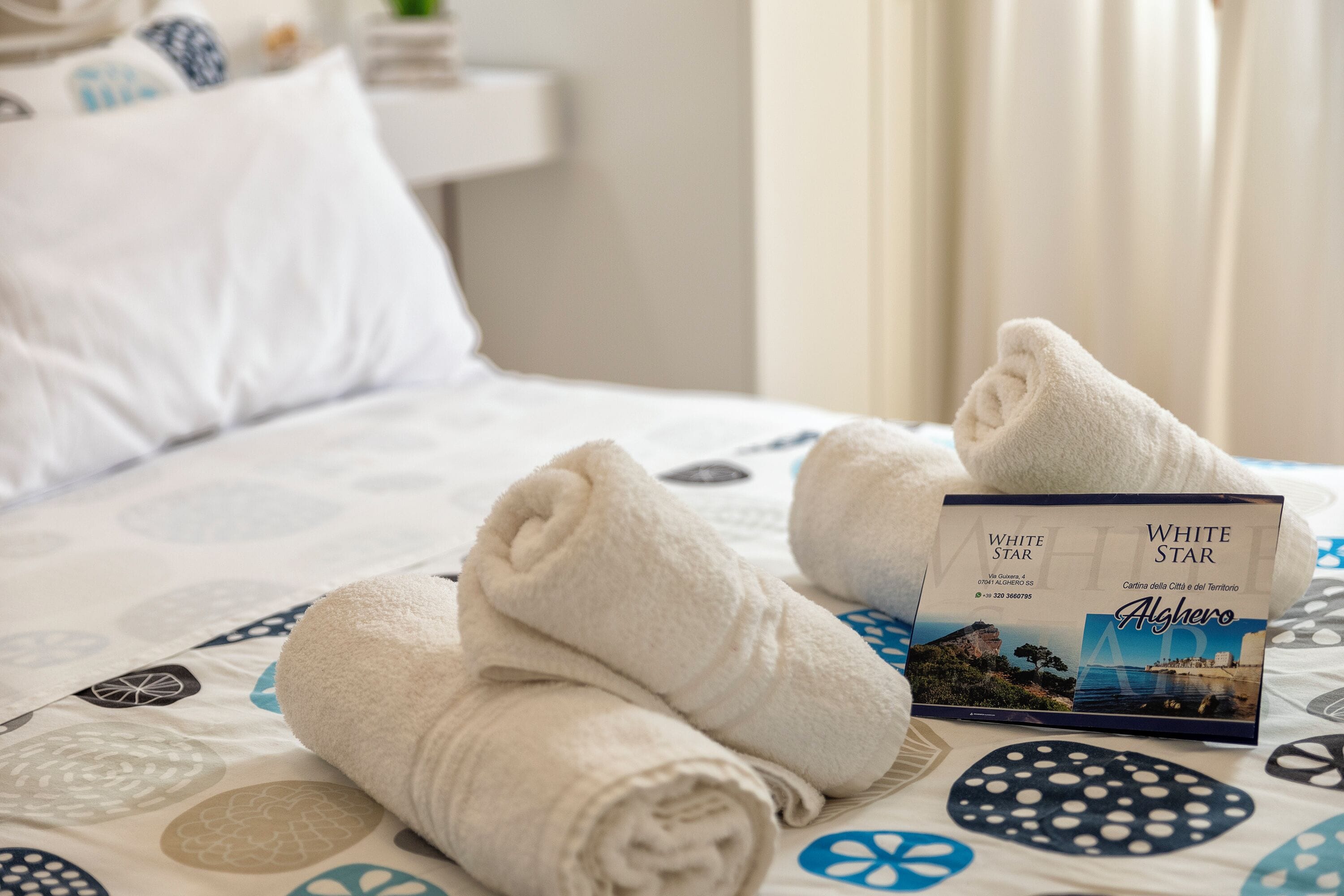 Un lit bien fait, avec des serviettes pliées et une brochure posée dessus.
