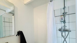 Un baño con lavabo, espejo, ducha y paredes de azulejos.