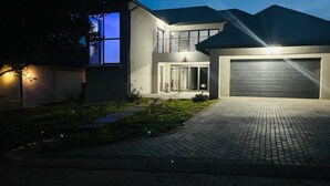A modern two-story house with a garage, a paved driveway, and a well-lit entrance. - The Perazim Place  (Hazyview)