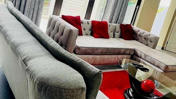 A modern living room with a grey sofa set, red cushions, and a glass coffee table. - The Perazim Place  (Hazyview)