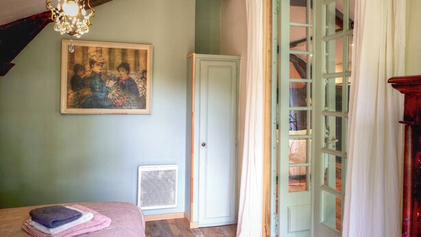 A bedroom with a bed, a radiator, a door, and a window with curtains. - Dordogne gite with pool, terrace and pond, charm & tranquility at Le Pigeonnier (Urval)