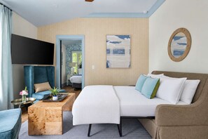 A hotel room with a bed, a sofa, a TV, a wooden coffee table, and a painting on the wall. - Victoria Retreat w. 2 King Suites & Shared Gym! (Charleston)