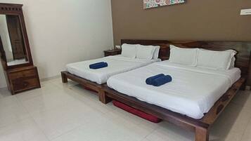 A hotel room with two single beds, a wooden headboard, a large mirror, and a colorful wall decoration.