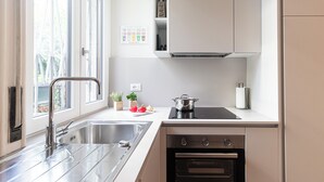 A modern kitchen with stainless steel appliances, a sink, and a window providing natural light. - Italianway Easy - Sebastiano Veniero 27 C - Bilo (Milan)