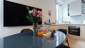 Une cuisine moderne avec une table à manger, un vase de fleurs et une table dressée pour le petit-déjeuner.