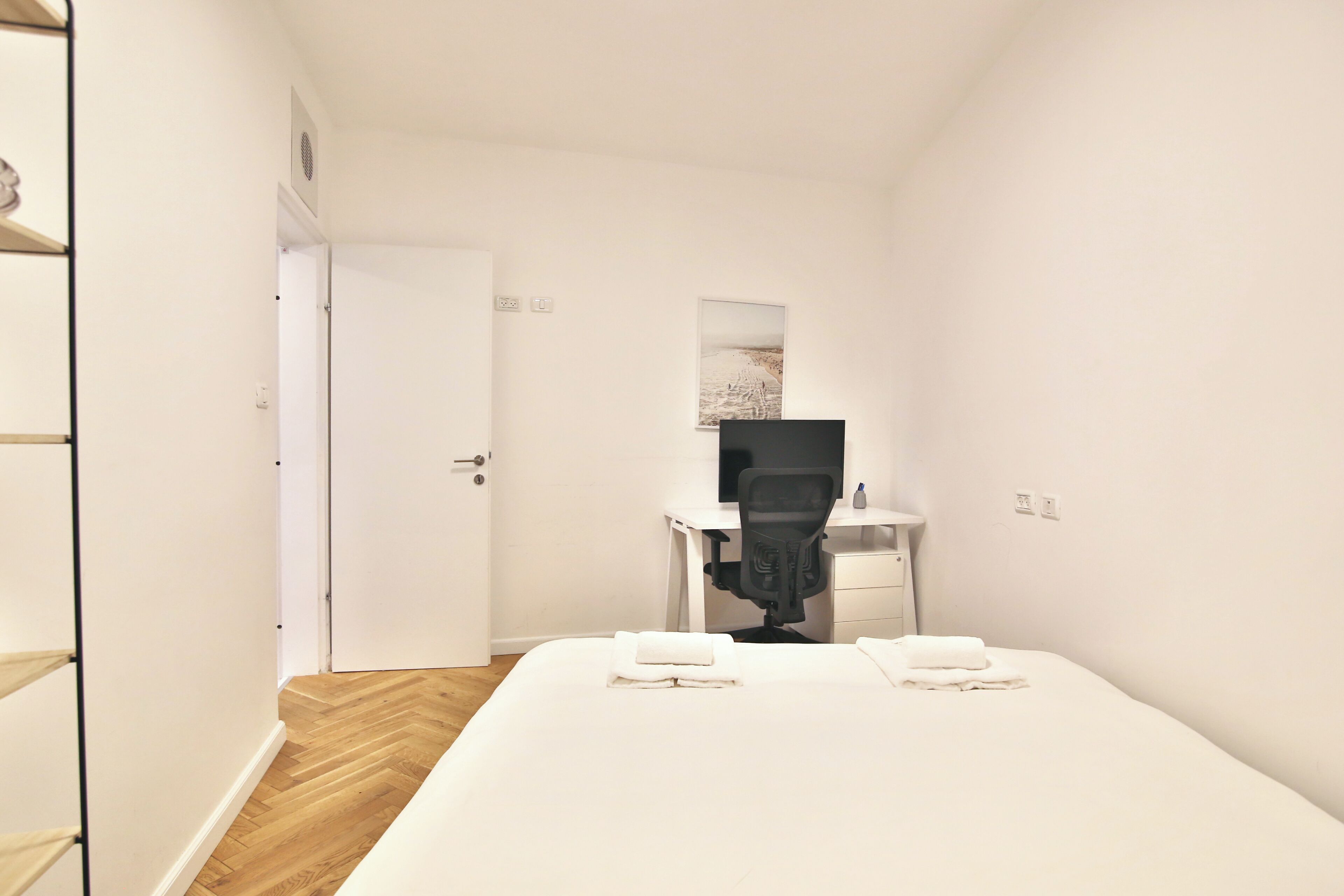Een hotelkamer met een bed, een bureau, een stoel en een deur.
