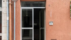 A building entrance with a glass door, a brick wall, and a utility box. - Lovely Terrace Apartment by Wonderful Italy (Bari)