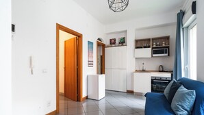 A modern apartment with a kitchen, a dining area, and a living room with a blue sofa. - Lovely Terrace Apartment by Wonderful Italy (Bari)