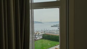Vista da janela sobre a água, com uma ponte e barcos.