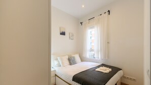 A bedroom with a bed, white walls, a window with curtains, and a radiator. - M Car1012 Apartamento con 2 Dormitorios 2 ba o (Madrid)