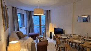 A modern living room with a sofa, ottoman, dining table set for four, and a TV. - Apartment 3R, 6 ppl, Valmorel with Parking (Valmorel)