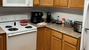 A kitchen with wooden cabinets, a white stove, a microwave, and a refrigerator.