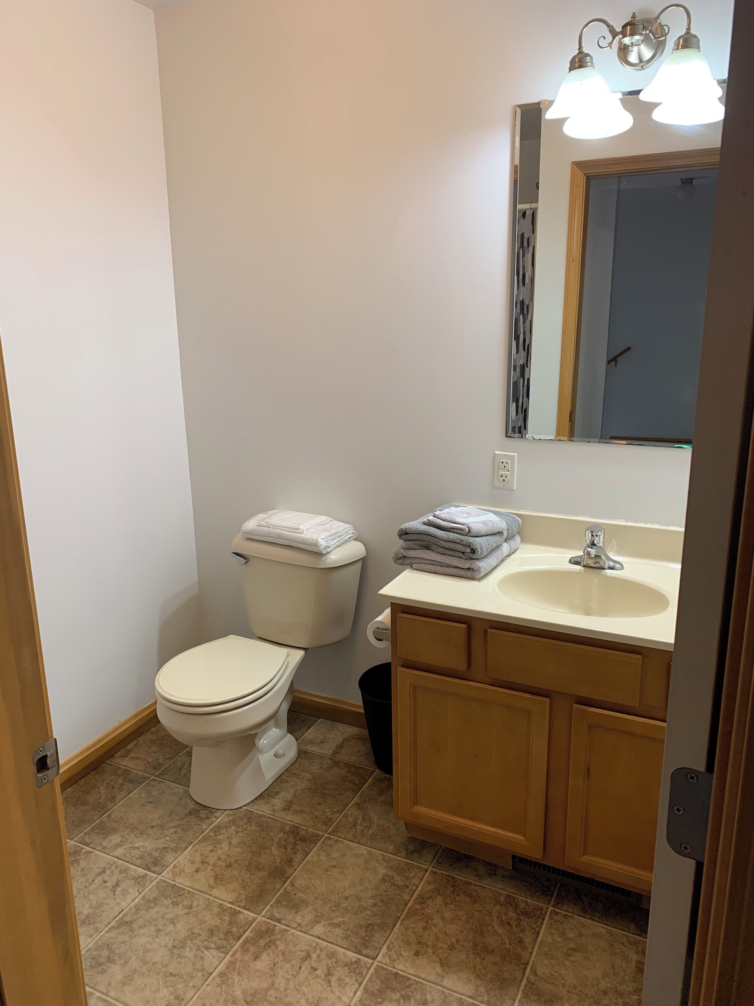 A small, clean bathroom with a toilet, sink, and mirror.