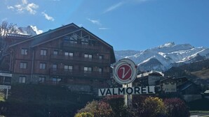 Un bâtiment en bois avec une enseigne indiquant « VALMOREL » et un panneau circulaire avec un « V » rouge à l’avant.