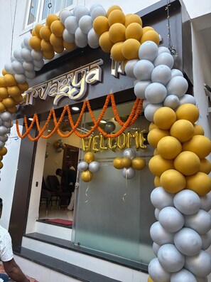 A building entrance decorated with balloons and garlands, with a sign that reads "Welcome". - Sarvagya Inn (Varanasi)