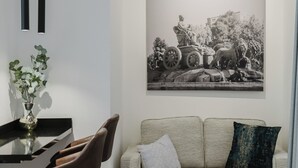 Moderni olohuone, jossa on sohva, sohvapöytä ja ruokailutila, jossa on tuoleja ja maljakko täynnä kukkia.
