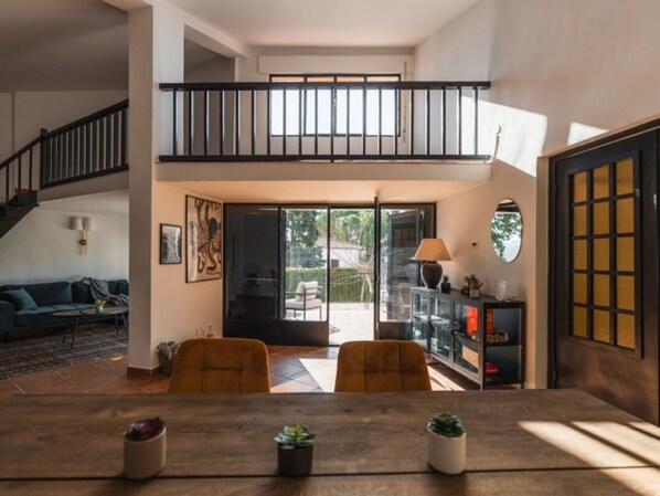 Un vaste espace de vie comprenant une table à manger, deux chaises, un canapé et un escalier menant à un niveau supérieur.