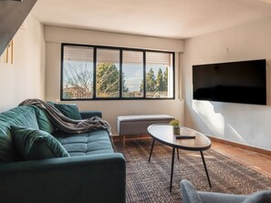 Un salon moderne avec un canapé, une petite table et un téléviseur fixé au mur.