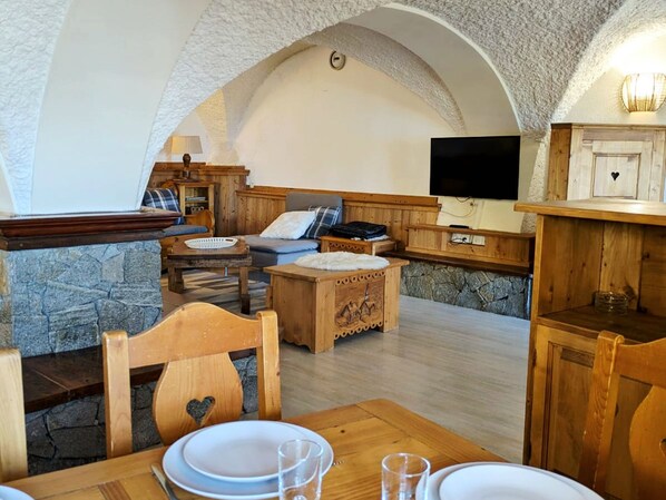 A cozy, rustic interior with stone walls, wooden furniture, and a stone fireplace.
