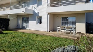 A two-story residential building with a balcony, a small patio with outdoor furniture, and a well-maintained lawn. - Ground floor T3 apartment, near Crouesty port, wifi, parking (Arzon)
