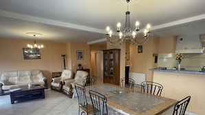 A dining area with a marble table, black chairs, a beige sofa, and a chandelier. - Ground floor T3 apartment, near Crouesty port, wifi, parking (Arzon)