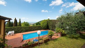 Un jardin avec une piscine, des plantes en pot et une vue sur le paysage.