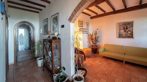 Un salon chaleureux avec un plafond en bois, un canapé, une table agrémentée d’objets décoratifs et une porte donnant sur une autre pièce.