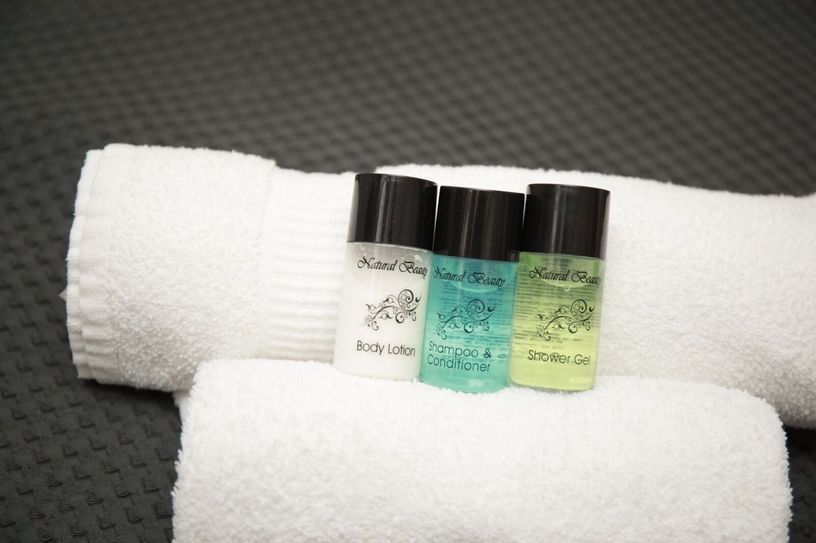 Tres botellas de productos de belleza naturales sobre una toalla blanca.