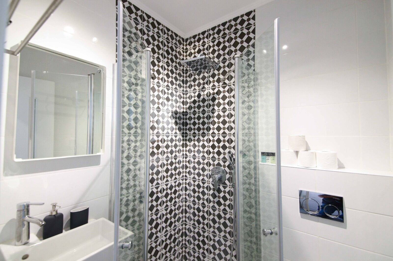 A modern bathroom with a glass shower enclosure, a white sink, and a mirror.