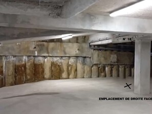 A parking garage with concrete walls, a ceiling with fluorescent lighting, and a sign indicating "N° 18". - Les Gets: 2-room flat, 4-6 pers, station center, garage (Les Gets)
